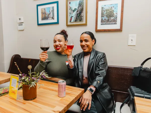 Two members of Colado Latino Network smiling and holding wine glasses at an event