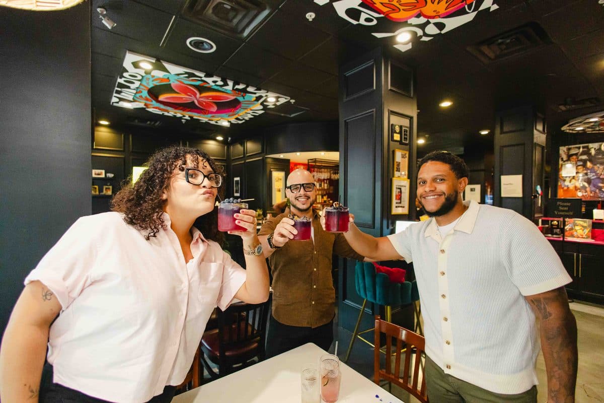 Three Colado Latino Network guests raising pink cocktails in a toast at The Empanada Lady in downtown Baltimore, MD