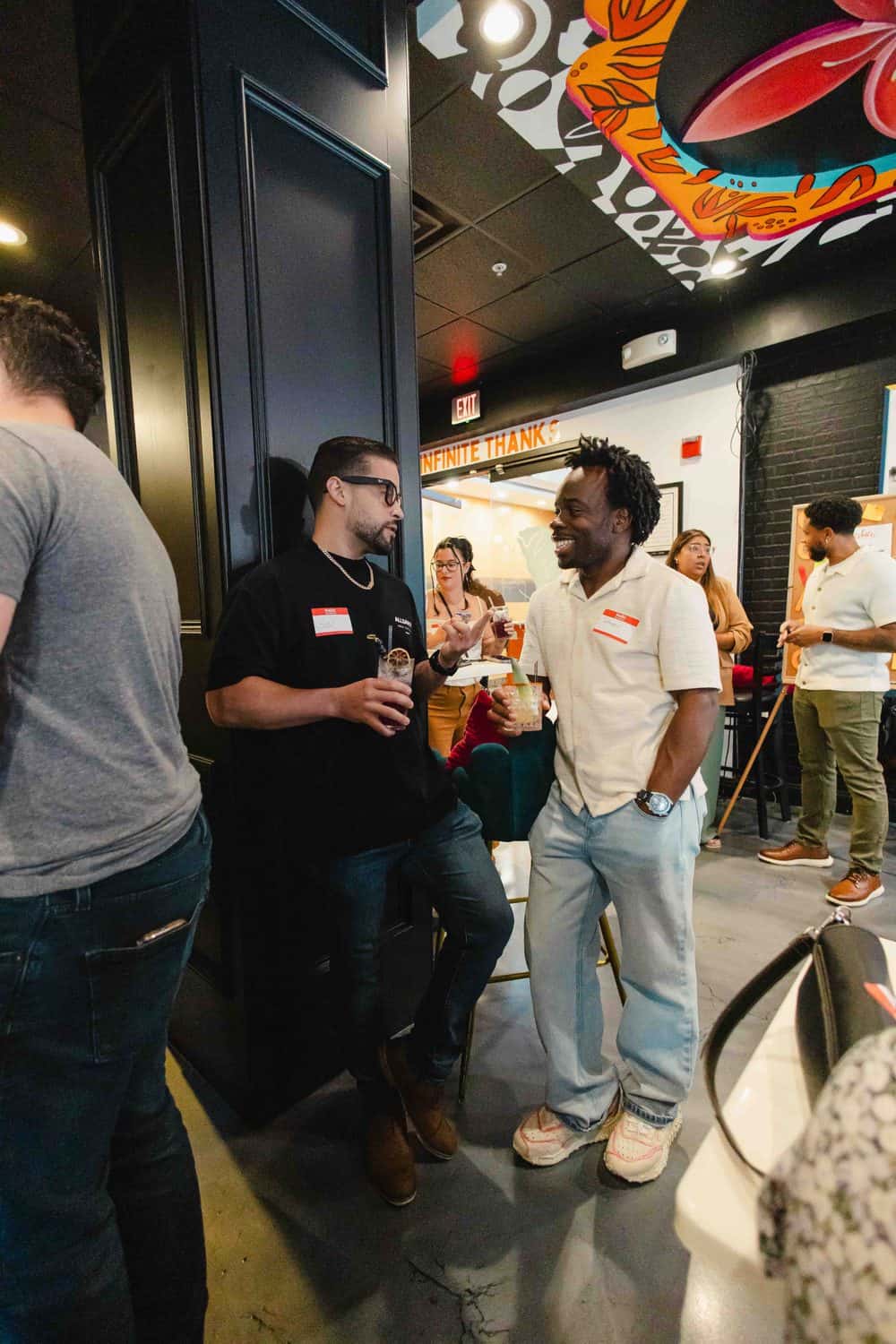 Two Colado Latino Network members wearing name badges laughing together at an event in Baltimore, MD