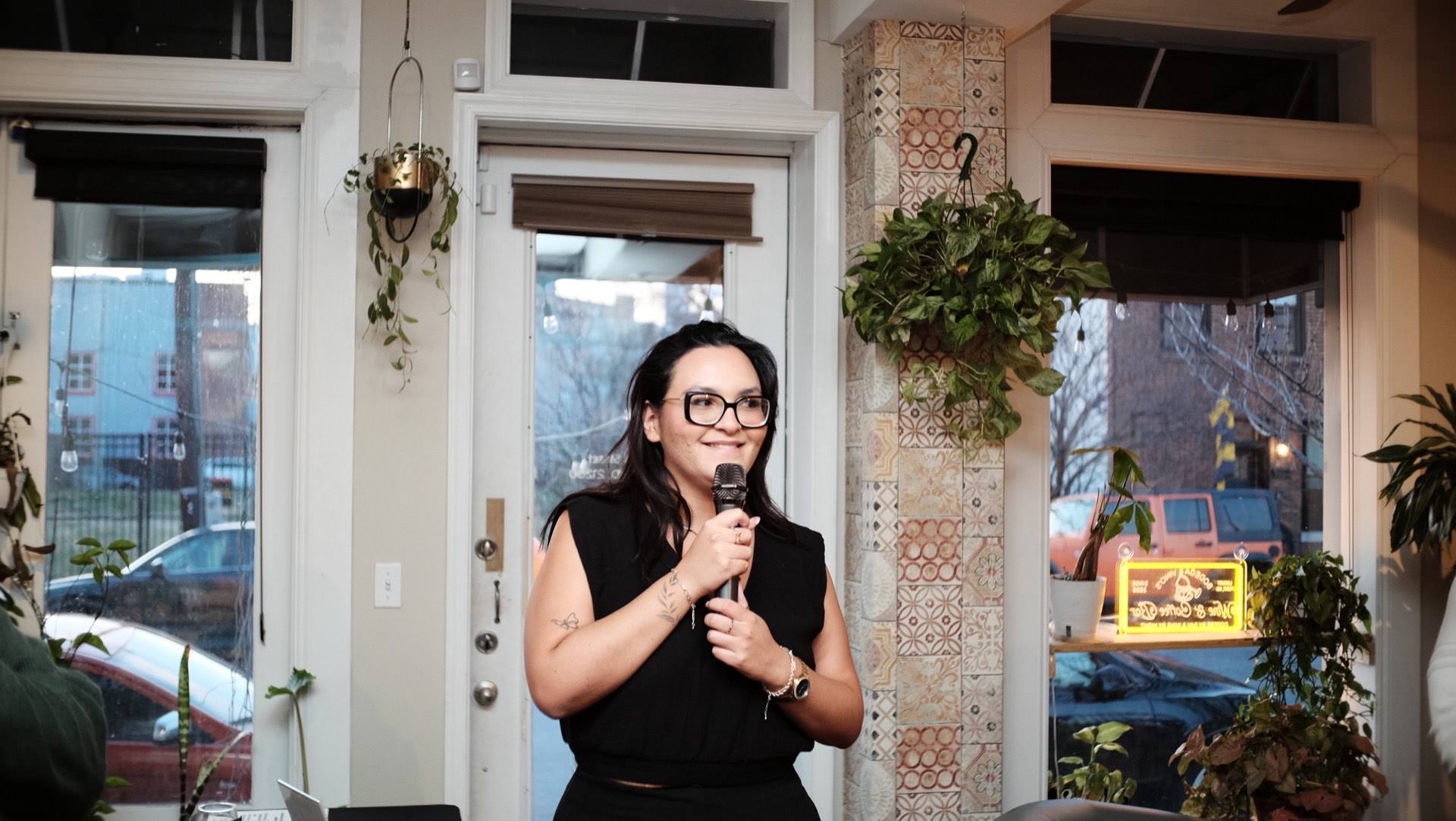 A Colado Latino Network team member on the microphone thanking the sold-out crowd at Bodega and Vino wine and coffee bar in Baltimore