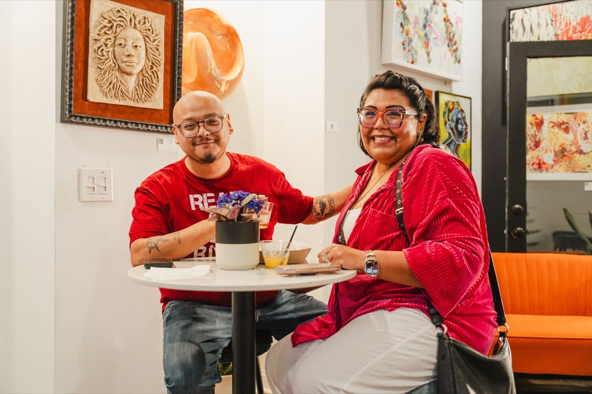 Two guests seated beside the art wall at Stem & Vine during the Colado Latino Network event in downtown Baltimore