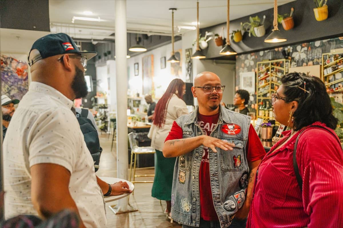 Guests talking and laughing among the plants at the Colado Latino Network event at Stem & Vine in downtown Baltimore