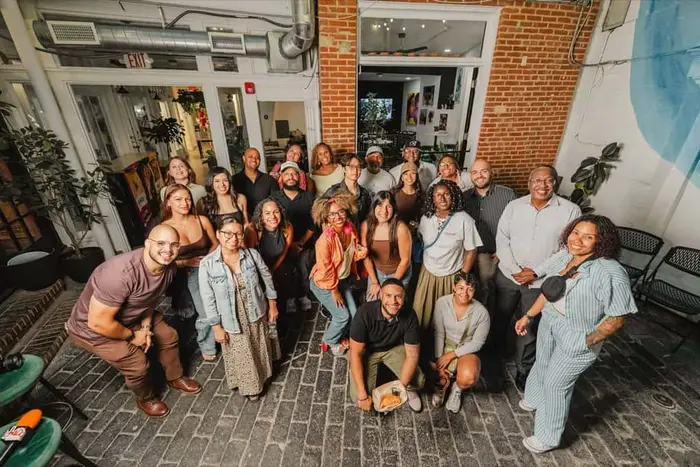 A wide group photo of Colado Latino Network guests gathered in the Stem & Vine courtyard in downtown Baltimore