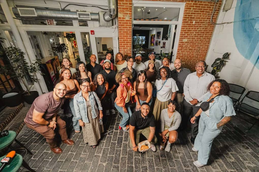 A wide group photo of Colado Latino Network guests gathered in the Stem & Vine courtyard in downtown Baltimore