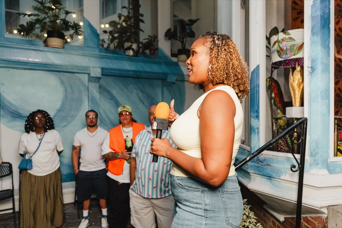 A guest speaking on the mic to the room during the Colado Latino Network event at Stem & Vine in downtown Baltimore